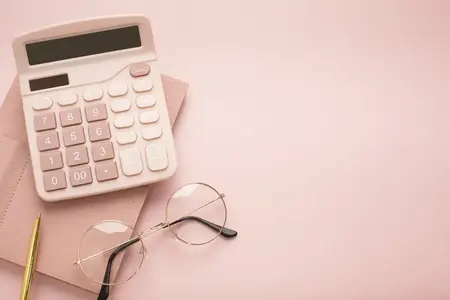 Calculatrice, lunettes et bloc-notes sur fond rose. Emplacement pour le texte