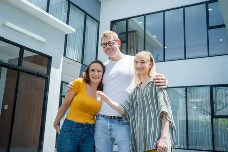 Fille tenant les clés avec leurs parents s'amusant ensemble devant leur nouvelle maison.