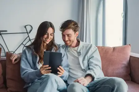 Couple souriant se détendant ensemble sur le canapé avec une tablette