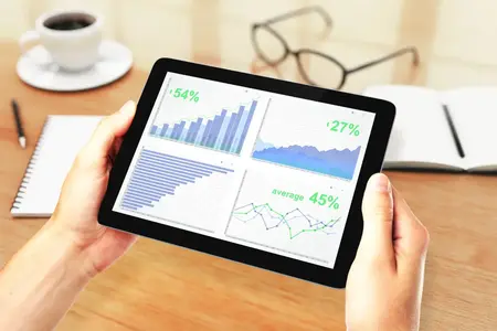 Mains d'hommes tenant une tablette numérique avec des graphiques financiers