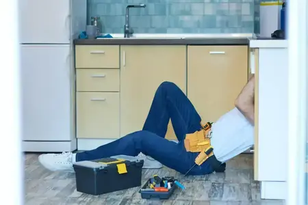 Service fiable. Réparateur professionnel, plombier examinant et fixant les tuyaux d'évier dans la cuisine