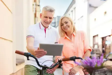 Un couple souriant utilise une tablette à vélo en ville
