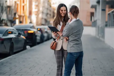 Deux femmes d'affaires utilisant une tablette et discutant du travail dans la rue de la ville