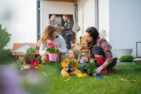 Famille multigénérationnelle heureuse à l'extérieur plantant des fleurs dans le jardin à la maison, concept de jardinage