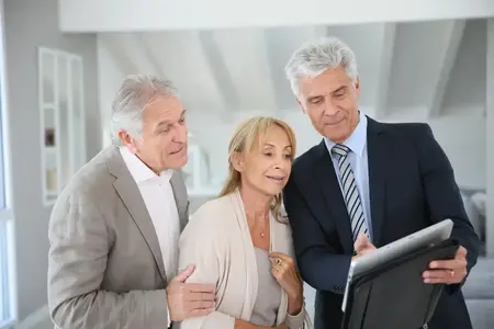 Un couple de retraités accompagné d'un agent immobilier visite une maison à vendre