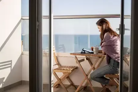 Une jeune femme dessine sur une tablette numérique sur la terrasse près de la mer