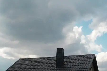 toit en acier sur fond de ciel sombre. Nuages de pluie sombres au-dessus du toit moderne. Toit avec nouveau toit noir