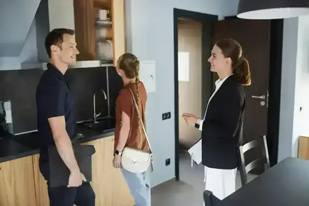 Un agent immobilier fait visiter une cuisine moderne à un couple.