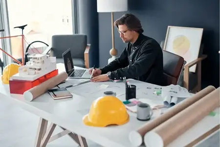 Shot of a handsome young architect working on building plans and designs in his office