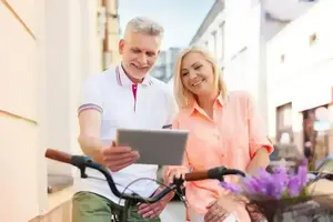 Un couple souriant utilise une tablette à vélo en ville