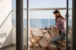 Une jeune femme dessine sur une tablette numérique sur la terrasse près de la mer